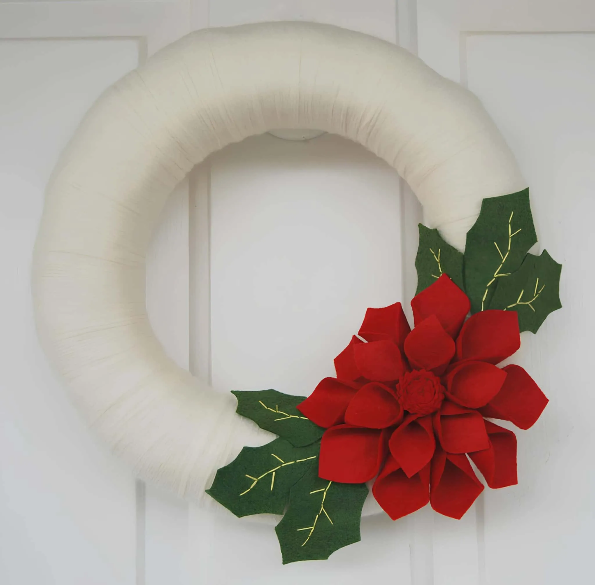 Weiße Filzkrone mit roter Poinsettia Minimalistische weiße Filz-Weihnachtskrone mit roter Poinsettia und grünen Blättern