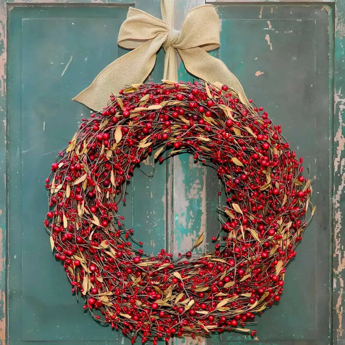 Roter Beeren-Weihnachtskranz Ländlicher Weihnachtskranz aus roten Beeren und Blättern, gebunden mit einem Weidenkorb-Bogen