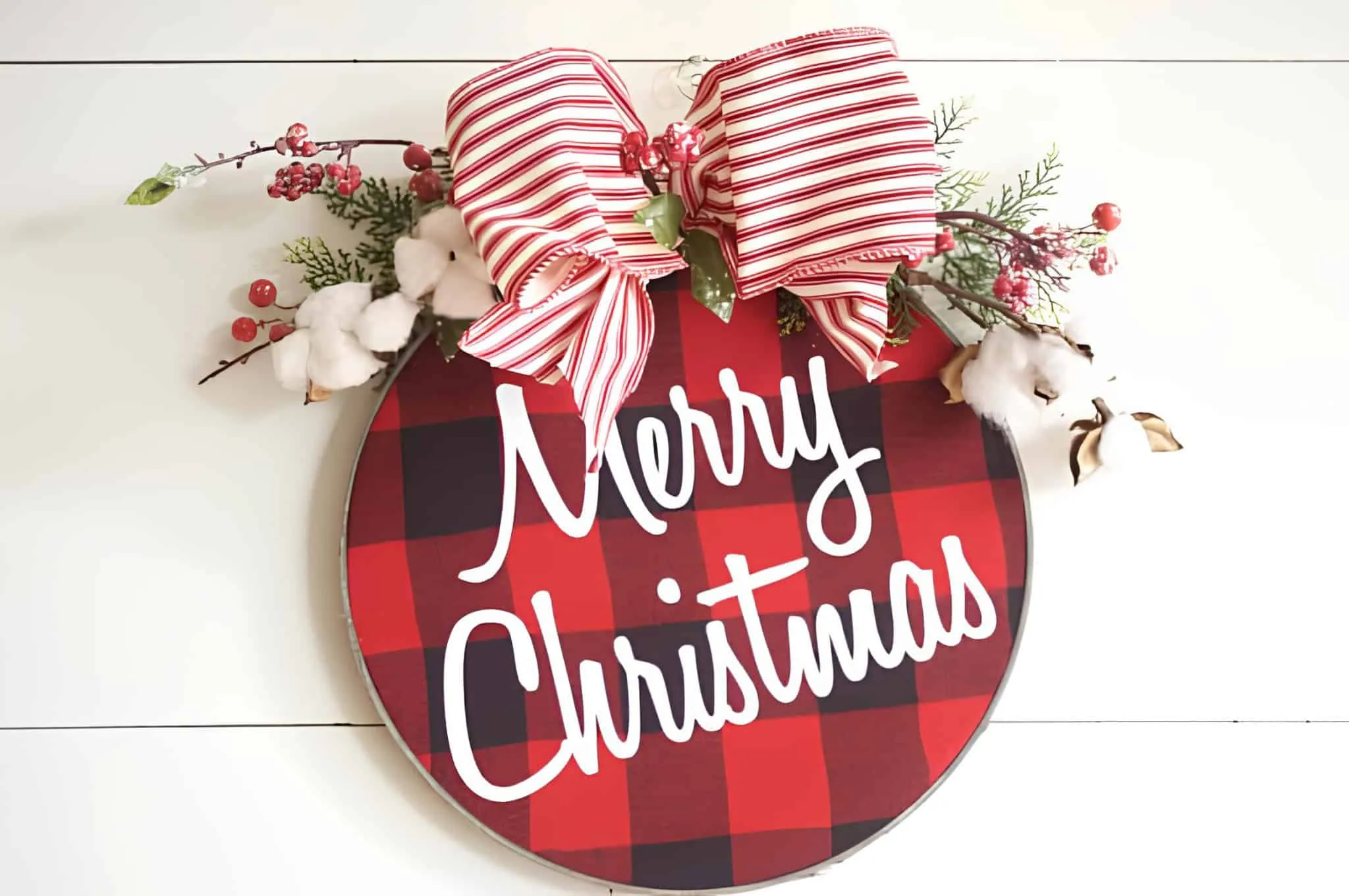 Runder Buffalo-Plaid-Türhänger mit gestreifter Schleife Buffalo-Plaid-Schild mit frohem Weihnachtsgruß, roter und weißer gestreifter Schleife sowie Baumwolle und Beeren