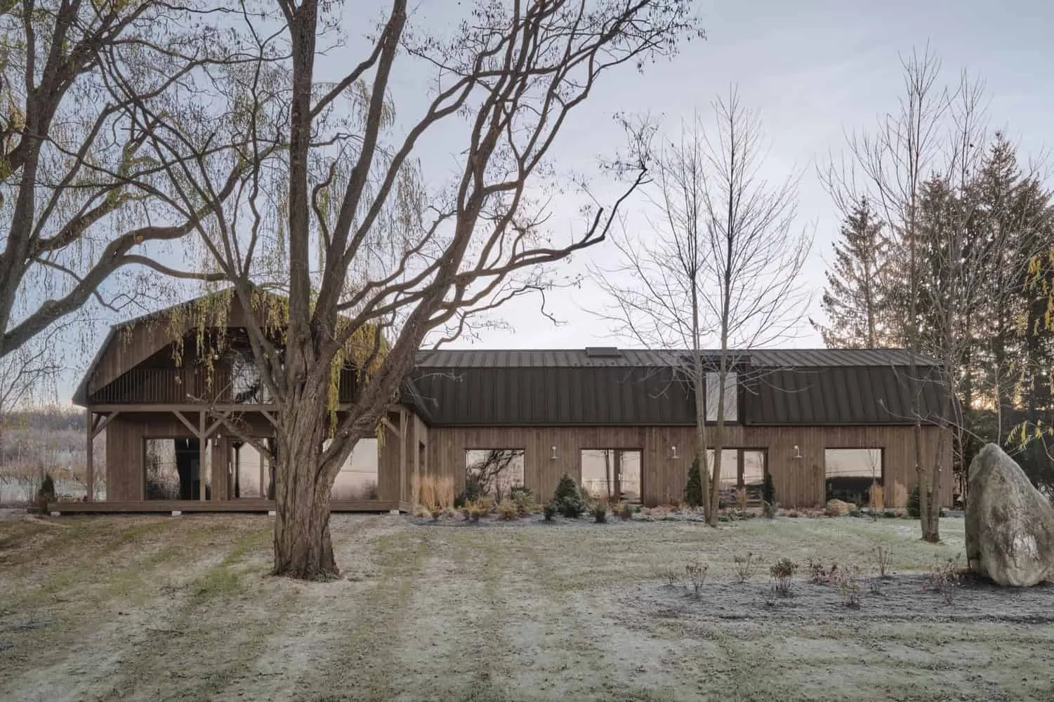 Maison Melba – Langansicht mit Bäumen im Vordergrund von Atelier L’Abri Langansicht der Maison Melba von Atelier L’Abri, umrahmt von ausgewachsenen Bäumen in Frelighsburg, Quebec