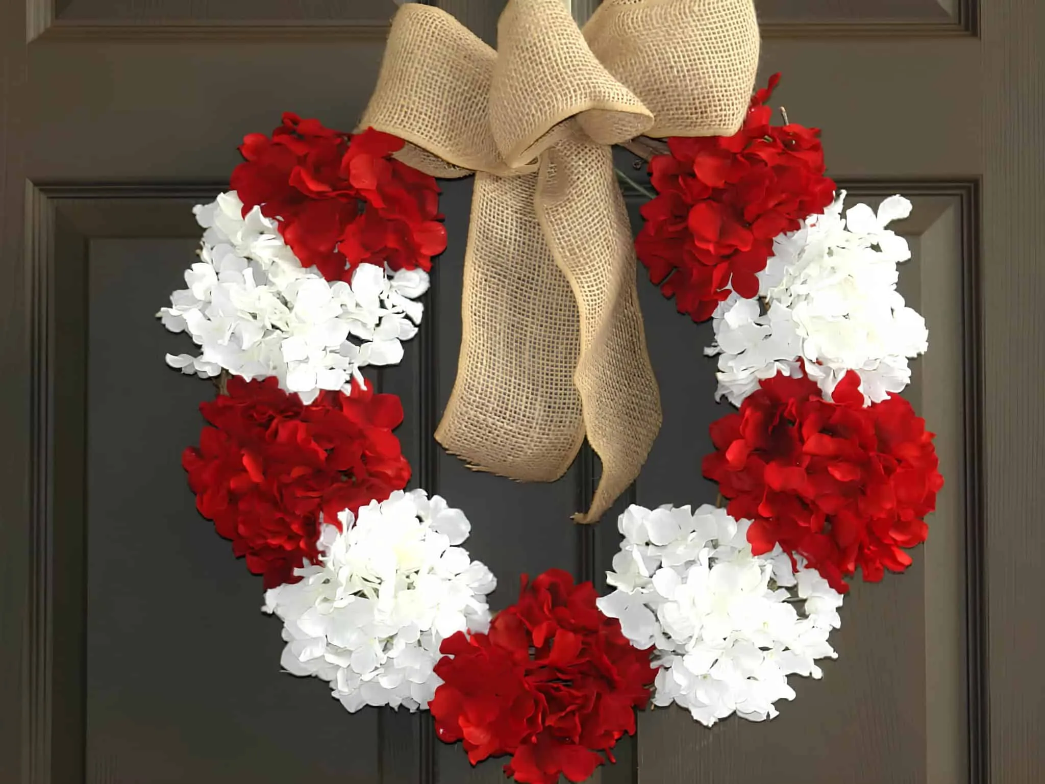 Roter und weißer Blumenkranz aus Jute in Bogenform Weihnachtskranz mit roten und weißen Hortensien sowie einem großen Jutebogen