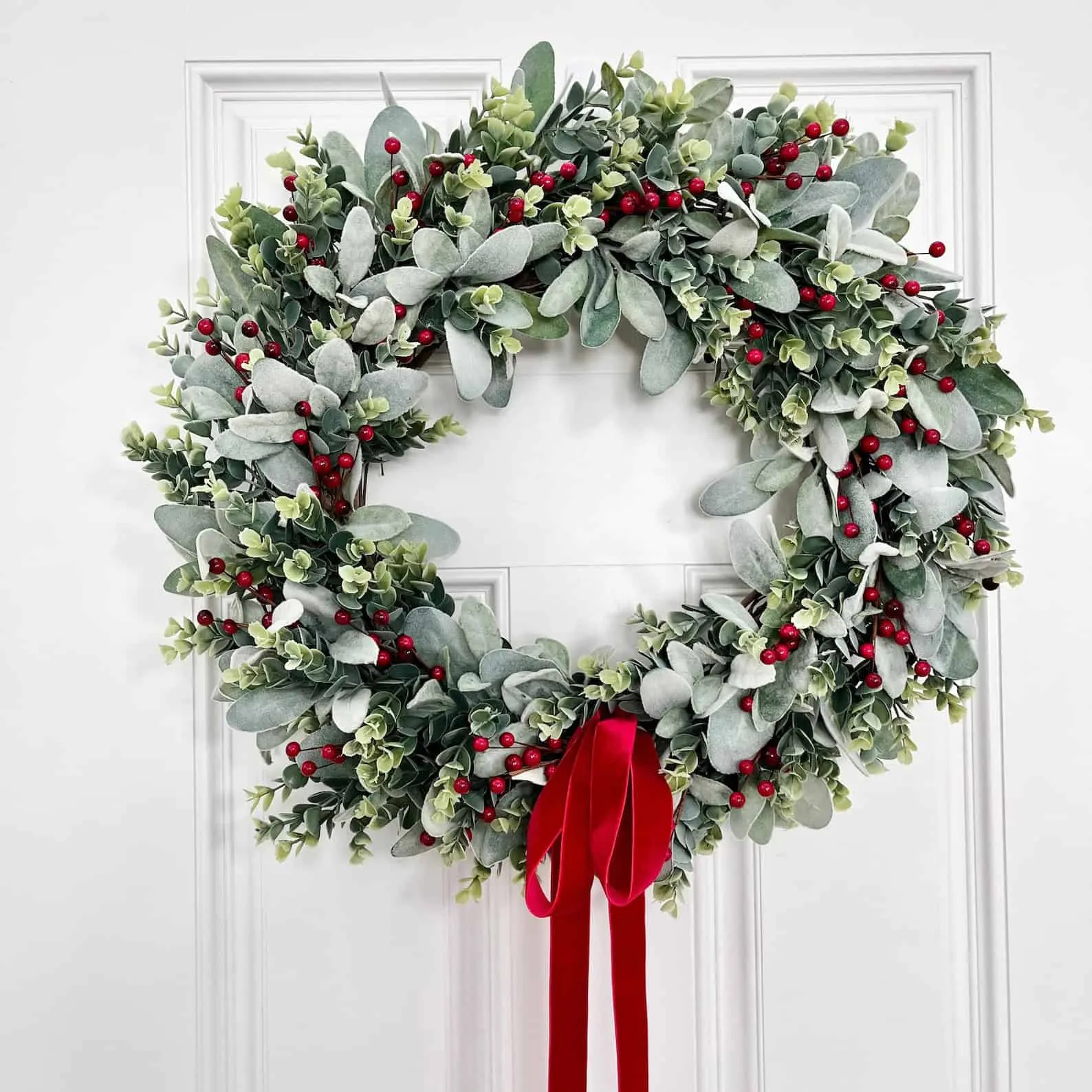 Weicher Schafohr-Kranz mit roten Beeren und Samtband Weicher Schafohr-Kranz mit roten Beeren und Samtband — klassischer Beerkranz für Weihnachten