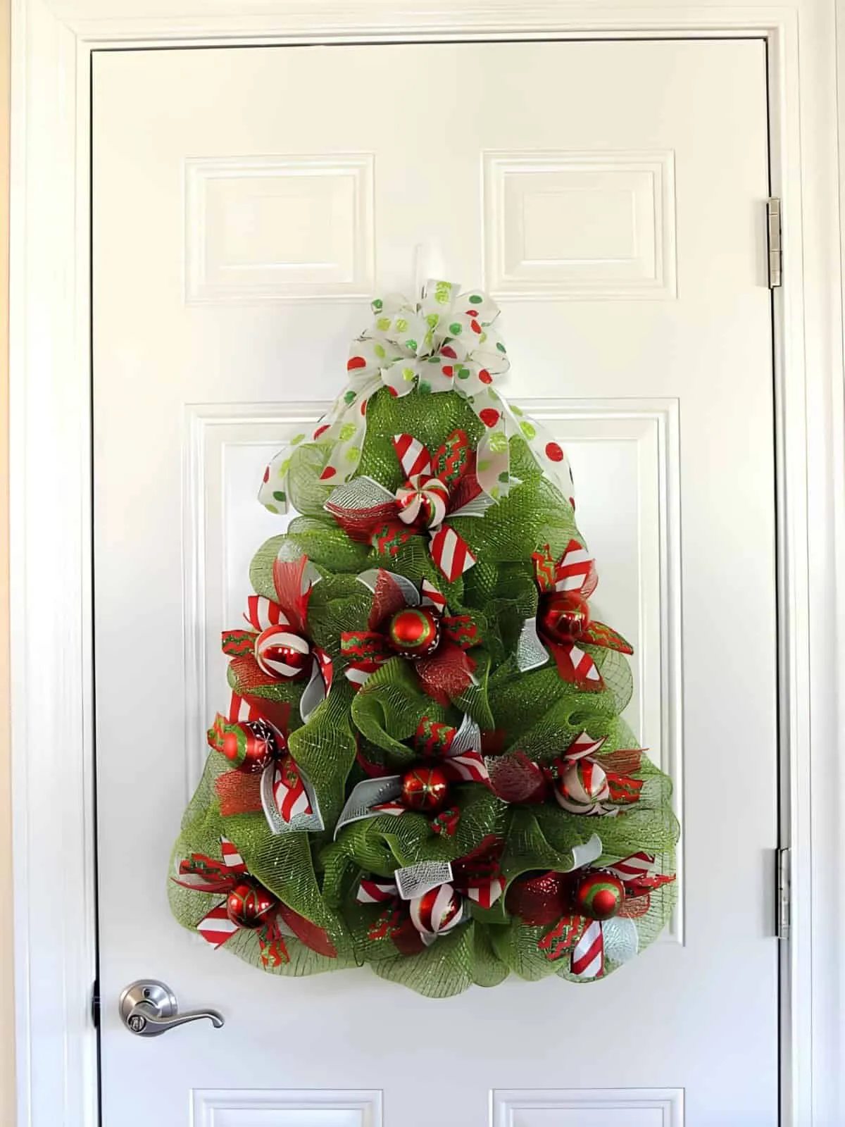 Weihnachtskrone in Form eines Baumes aus Bändern Weihnachtskrone in Form eines Baumes mit grünem Netz und roten Bändern
