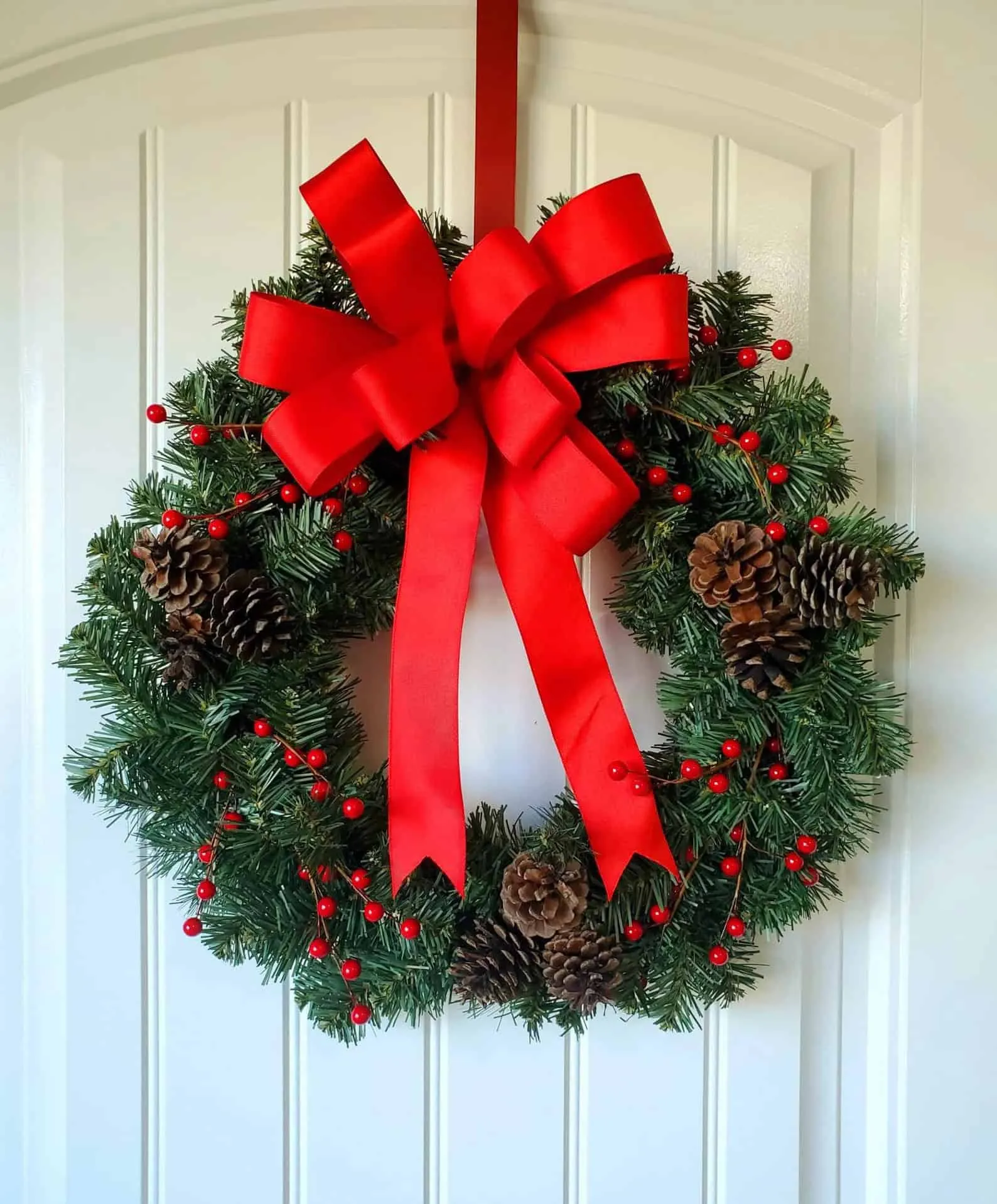 Pinecone and Berry Christmas Wreath Klassische Weihnachtskrone aus Kiefernzapfen mit roten Beeren und immergrünem Laub