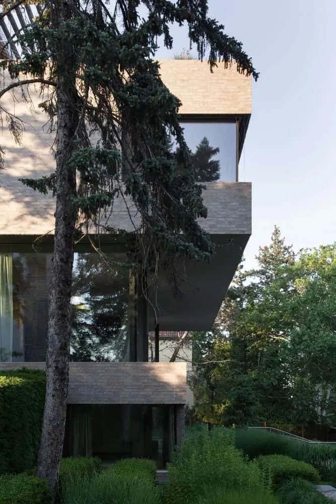 Seitliche Ansicht der Villa Vista mit Gartenbereichen von Znameni Ctyr Architekti Villa Vista von Znameni Ctyr Architekti, seitliche Ansicht mit mehreren Ebenen, die in einen üppigen Garten abfallen