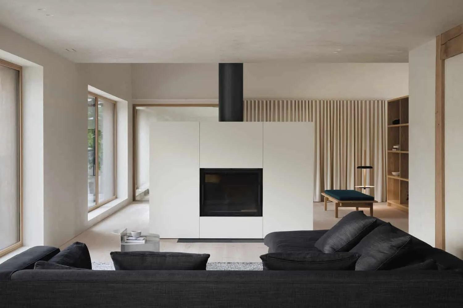 Wohnzimmer von Maison Melba mit Kamin und schwarzem Sofa von Atelier L’Abri Wohnzimmer von Maison Melba von Atelier L’Abri mit zentraler Feuerstelle und dunklem modernem Sofa in Frelighsburg, Quebec