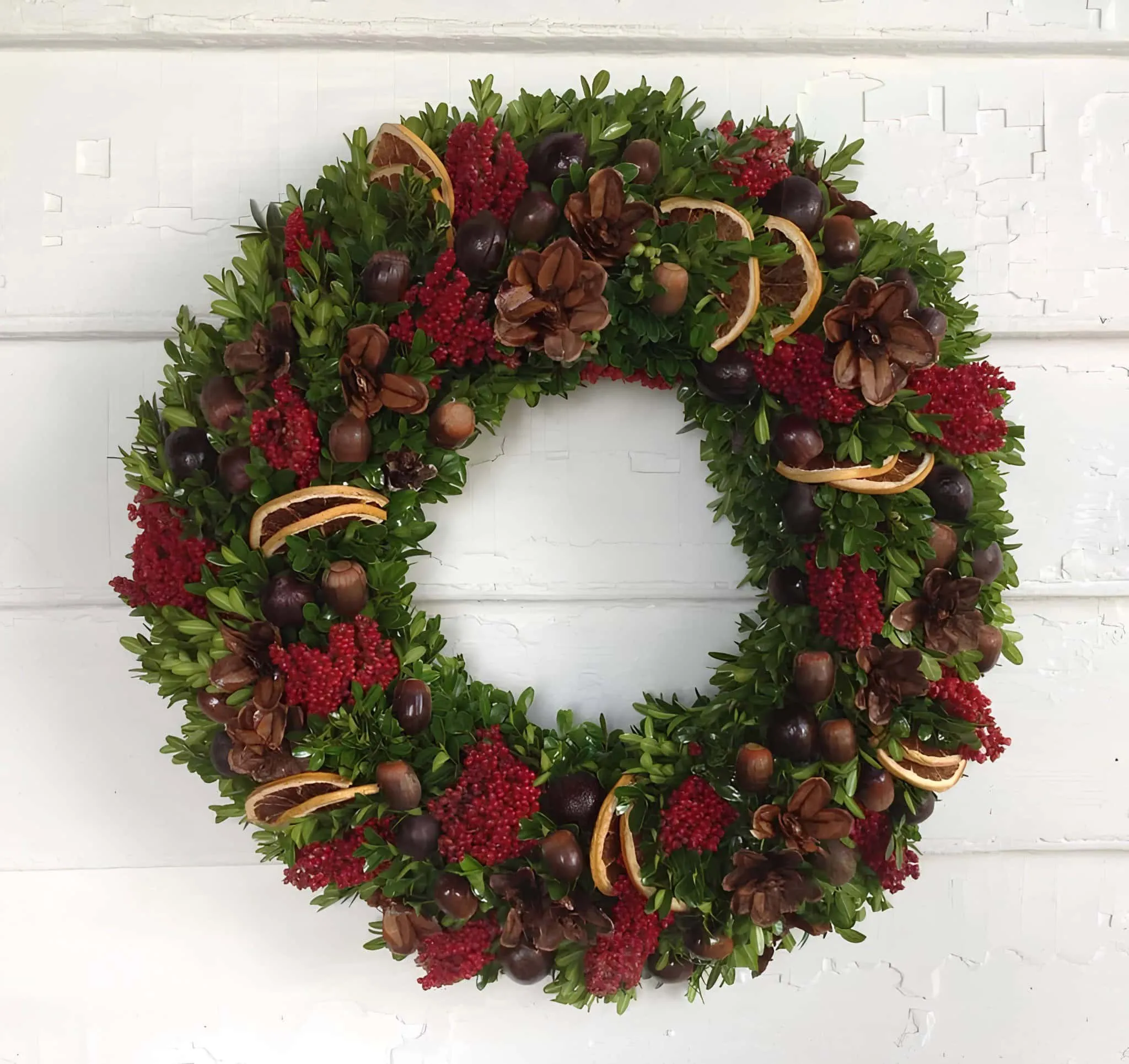 Weihnachtskranz mit getrockneten Orangen und Kiefernzapfenbeeren Naturbelassener Weihnachtskranz mit getrockneten Orangenscheiben, Kiefernzapfen, roten Beeren und Grünzeug