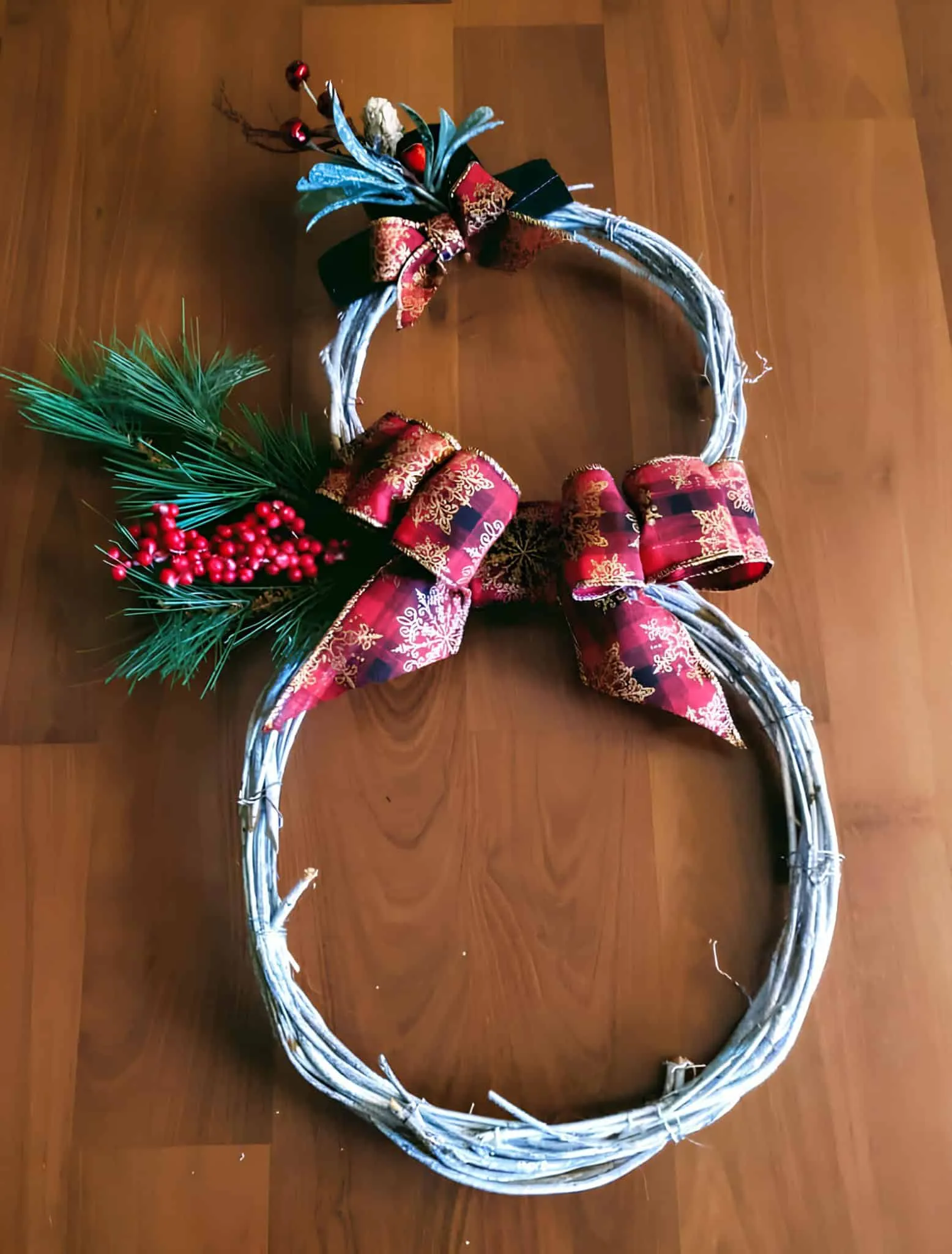 Twig-Schneemann-Kranz mit karierten Bändern Festlicher Weihnachtskranz mit roten Bändern, Kiefernzweigen und Beeren für die Dekoration des Ferienhauses.