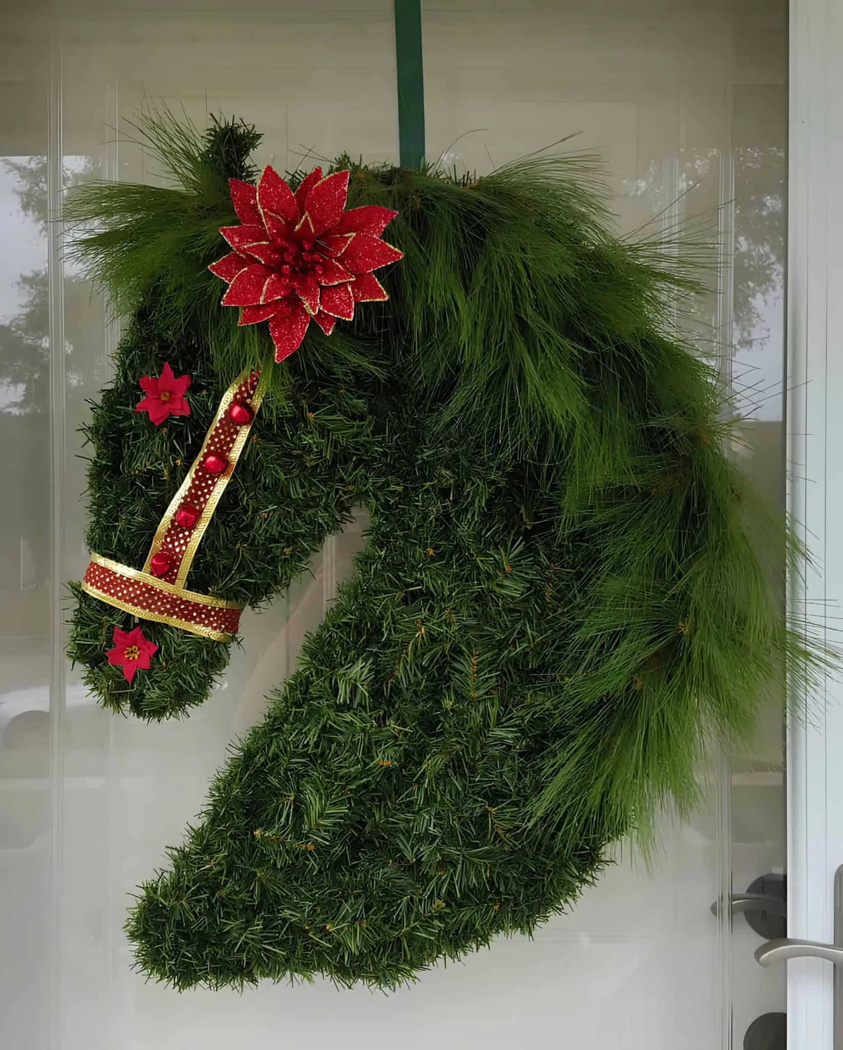 Weihnachtskranz in Form eines Pferdekopfes Einzigartiger Weihnachtskranz in Form eines Pferdekopfes mit roten Poinsettienblüten und Kieferngrün