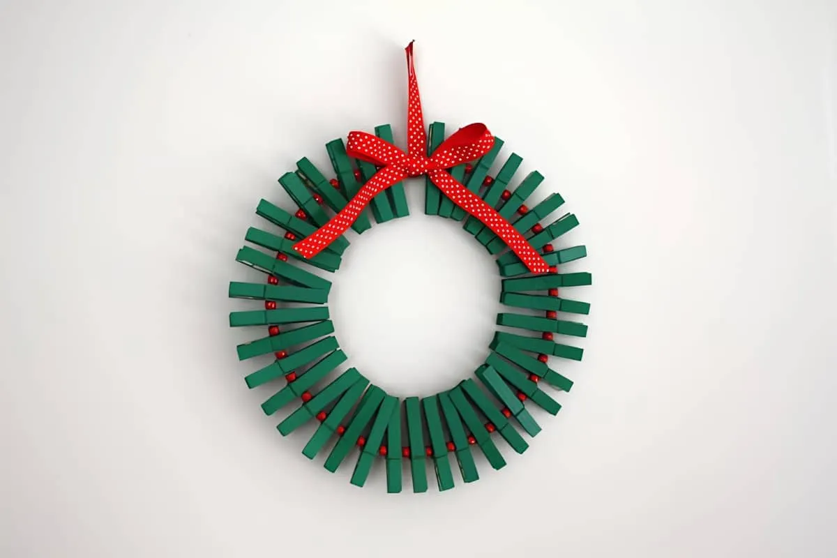Grüner und roter Weihnachtskranz mit Wäscheklammern Selbstgemachter Weihnachtskranz aus grünen Wäscheklammern und roten Perlen