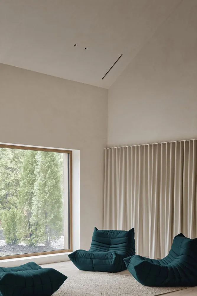 Maison Melba – Grüne Sitzmöbel am großen Bildfenster von Atelier L’Abri Maison Melba von Atelier L’Abri mit grünen Sitzmöbeln vor einem großen Bildfenster in Frelighsburg, Quebec