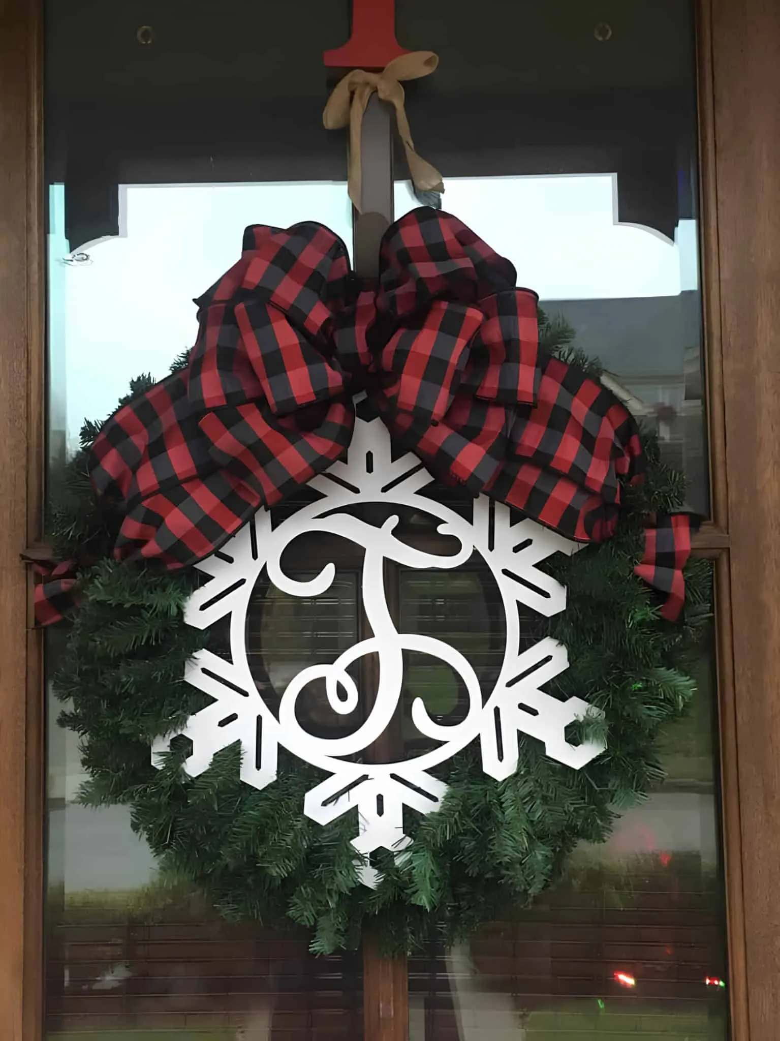 Immergrüne Monogramm-Schneeflockenkrone mit Buffalo-Plaid-Binde Klassische Immergrünenkrone mit weißer Monogramm-Schneeflocke und Buffalo-Plaid-Binde