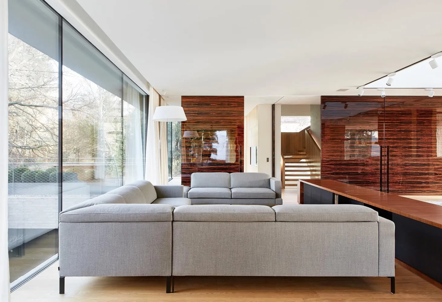 Wohnzimmer der Villa Vista mit Holzpaneelen von Znameni Ctyr Architekti Wohnzimmer der Villa Vista von Znameni Ctyr Architekti in Prag mit grauen Sofas und glänzenden Holzwandpaneelen
