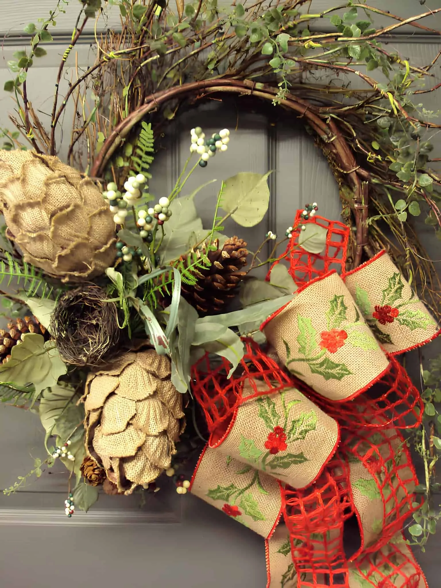 Ländliche Weidenstoff- und Stechpalmenholz-Weihnachtskranz Ländlicher Holz-Weihnachtskranz auf einer Rebenbasis mit Weidenstoff-Stechpalmenborte, Kiefernzapfen und Grünzeug