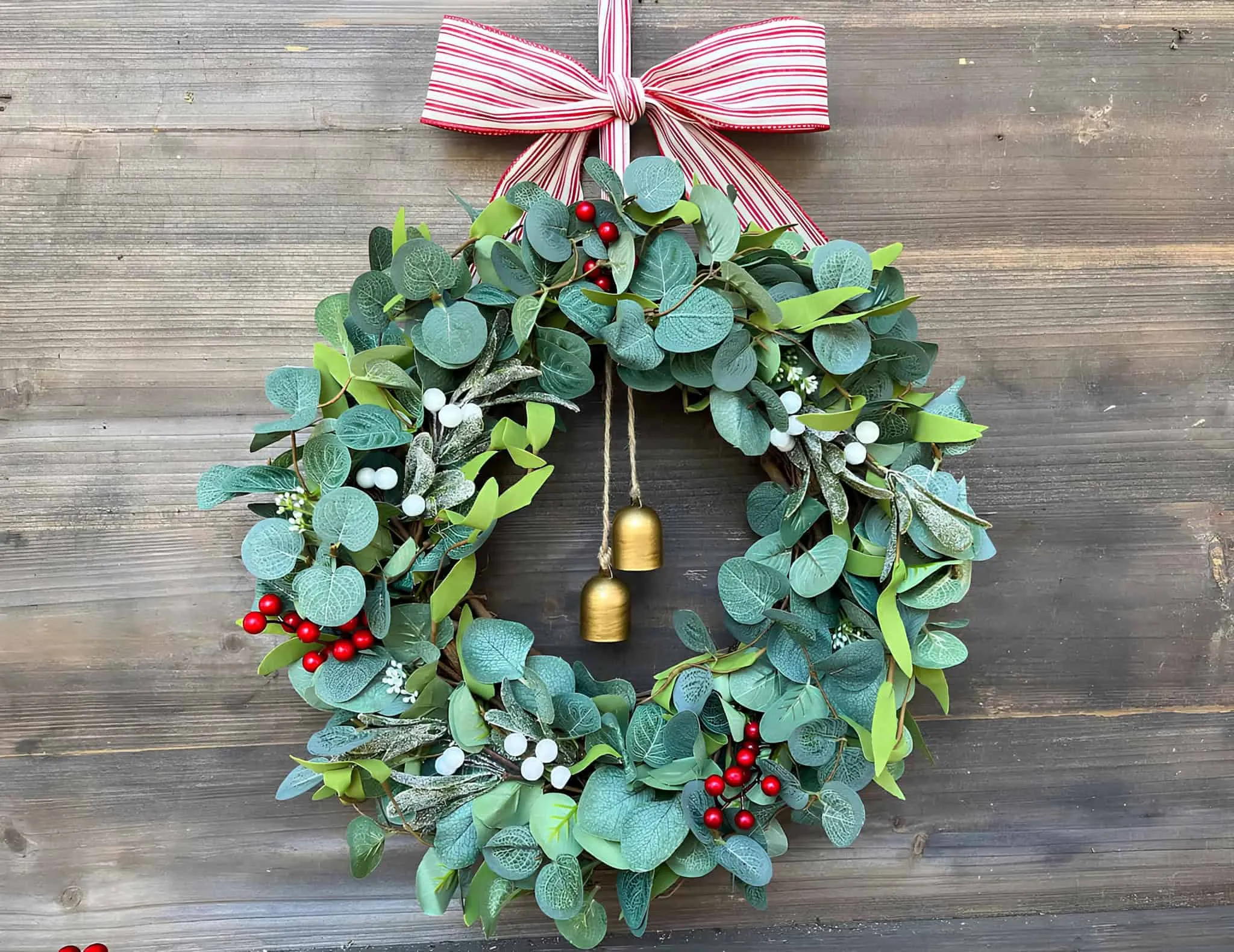 Weihnachtskranz aus Eukalyptus und Glocken Weihnachtskranz aus Eukalyptus mit goldenen Glocken und roten Beeren