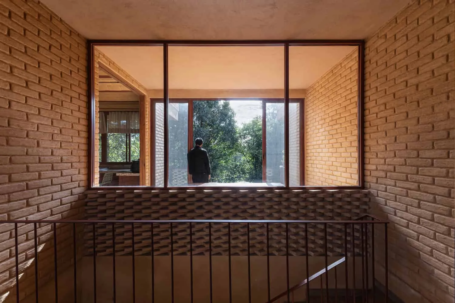 Valdez Arquitectos द्वारा डिज़ाइन किया गया The Sierra House में ईंटों से बना लैंडिंग क्षेत्र, जिसमें बड़ी खिड़की से मेक्सिको के चियापास में स्थित जंगल का नज़ारा दिखाई देता है