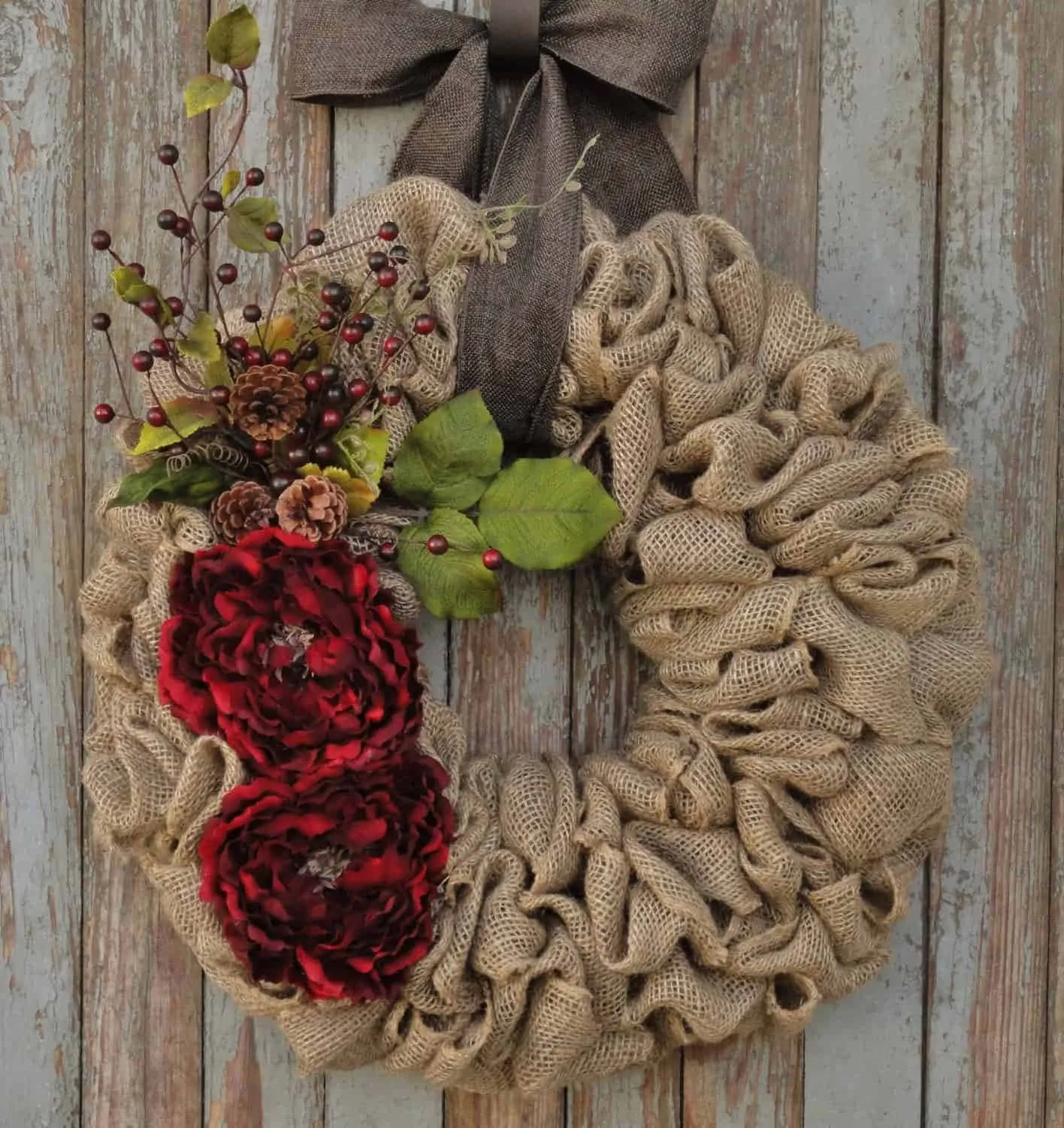 Rote Blumengirlande aus Leinwand mit Schleife – Weihnachtskranz Leinwandkranz mit roten Blumen, Kiefernzapfen, Grünzeug und brauner Schleife