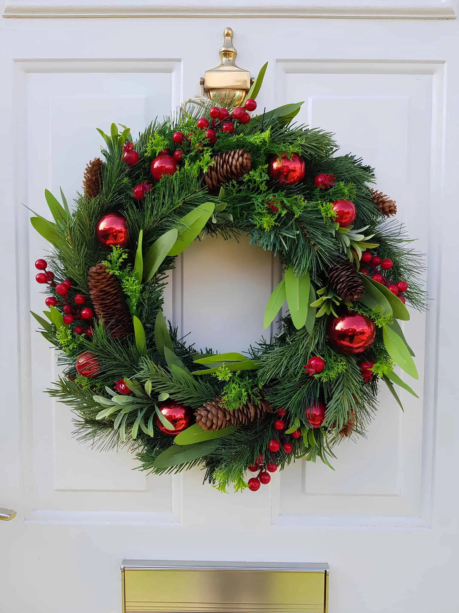 Klassische rote Dekoration & Tannenzapfen-Weihnachtskranz Traditioneller Tannenzweigkranz mit roten Dekorationen, Beeren und Tannenzapfen