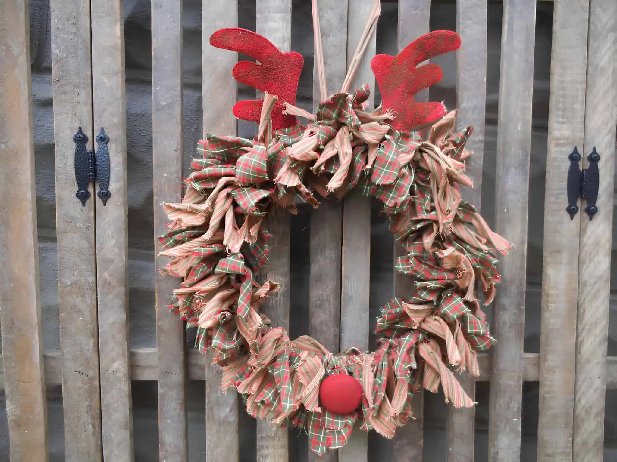 Weihnachtskranz aus kariertem Rentierstoff Weihnachtskranz aus kariertem Stoff mit roten Rentierhörnern und rustikalem Charakter