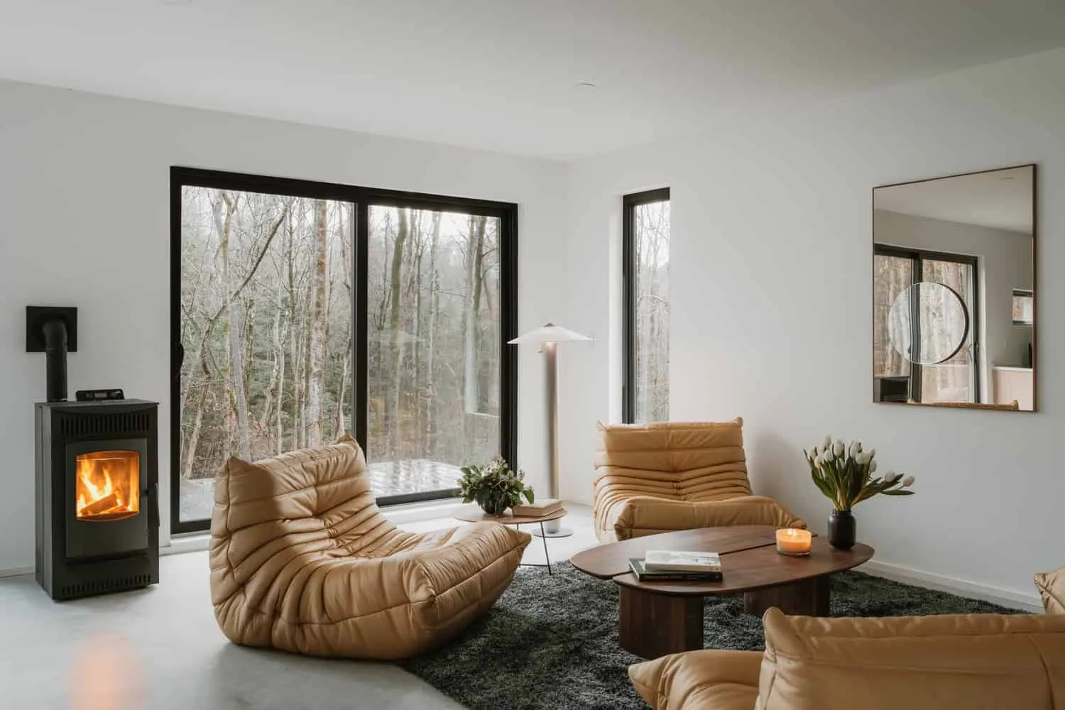 Wohnzimmer des Forest Edge House von Marc Thorpe Design Wohnliches Wohnzimmer im Forest Edge House mit Sesseln und Herd mit Blick auf den Wald