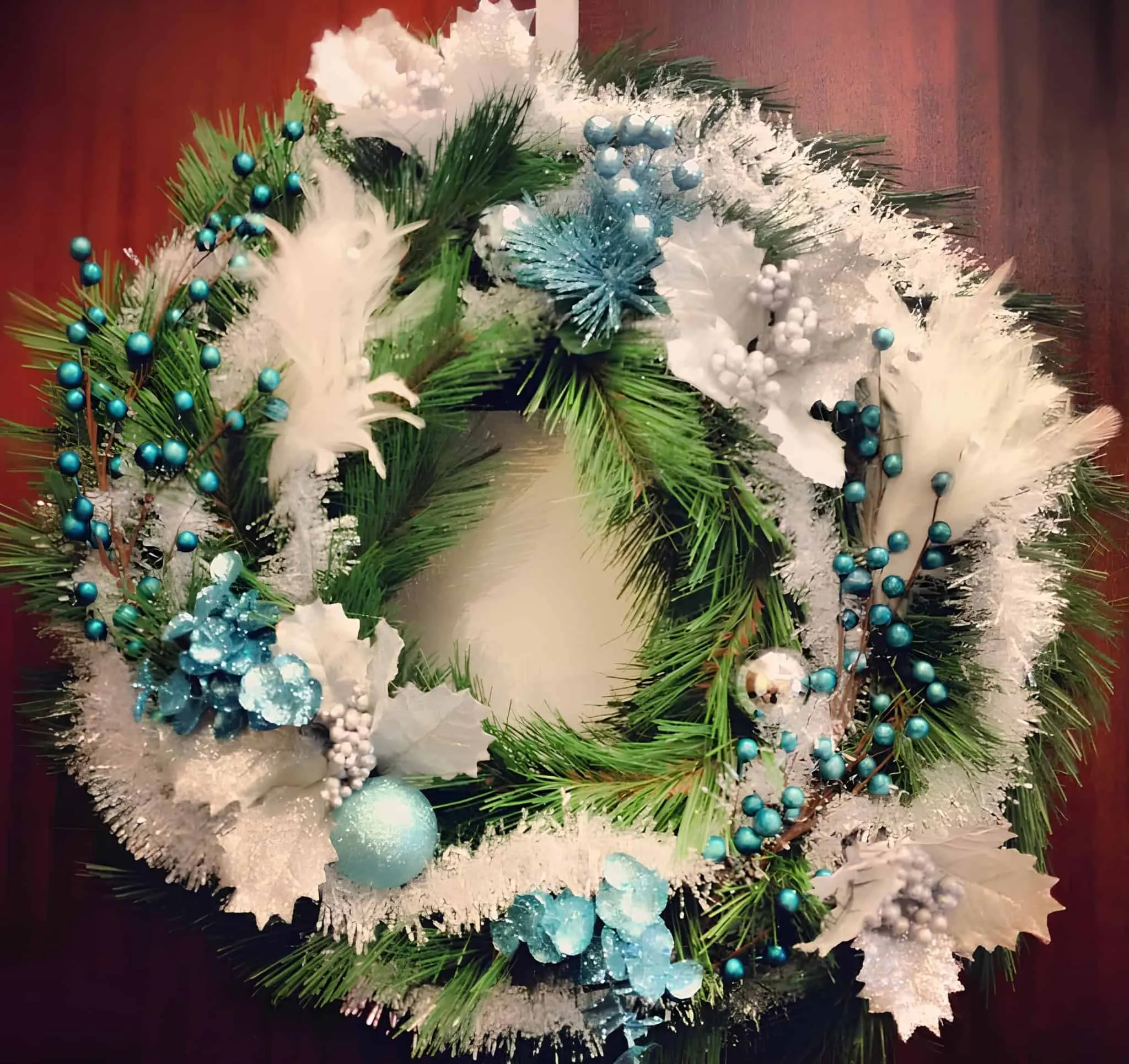 Weihnachtskranz aus bemalter Kiefer in Blau und Weiß Bemalter Kiefernkranz, verziert mit blauen Ornamenten, weißen Federn und eisigen Blättern