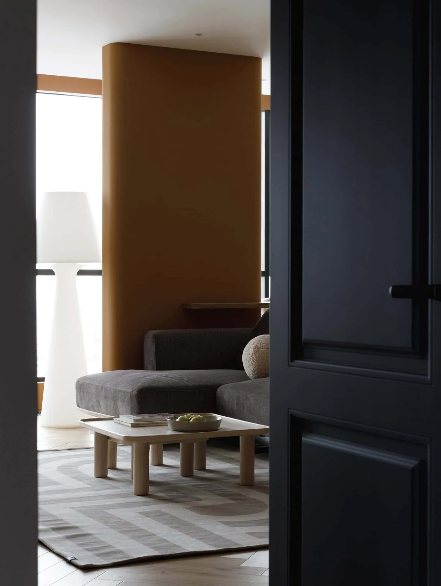 Ansicht der Wohnzimmertür in der Lesoparkovy-Wohnung von STARIKOVA.ARCHITECTS Ansicht des warmtonigen Wohnzimmers mit Sofa und Lampe in der Lesoparkovy-Wohnung von STARIKOVA.ARCHITECTS