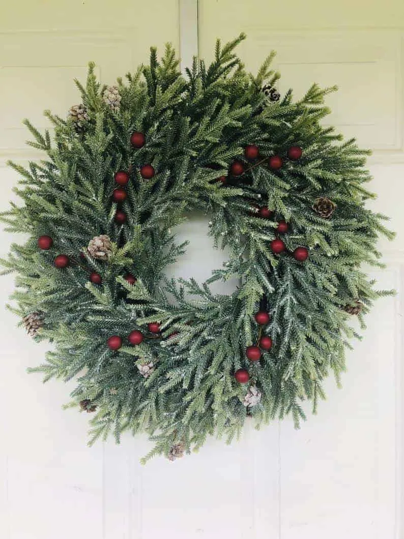 Gefroster Kiefernkränzchen mit matten roten Beeren Gefroster Kiefern-Weihnachtskränzchen mit matten roten Beeren und schneeweißen immergrünen Pflanzen
