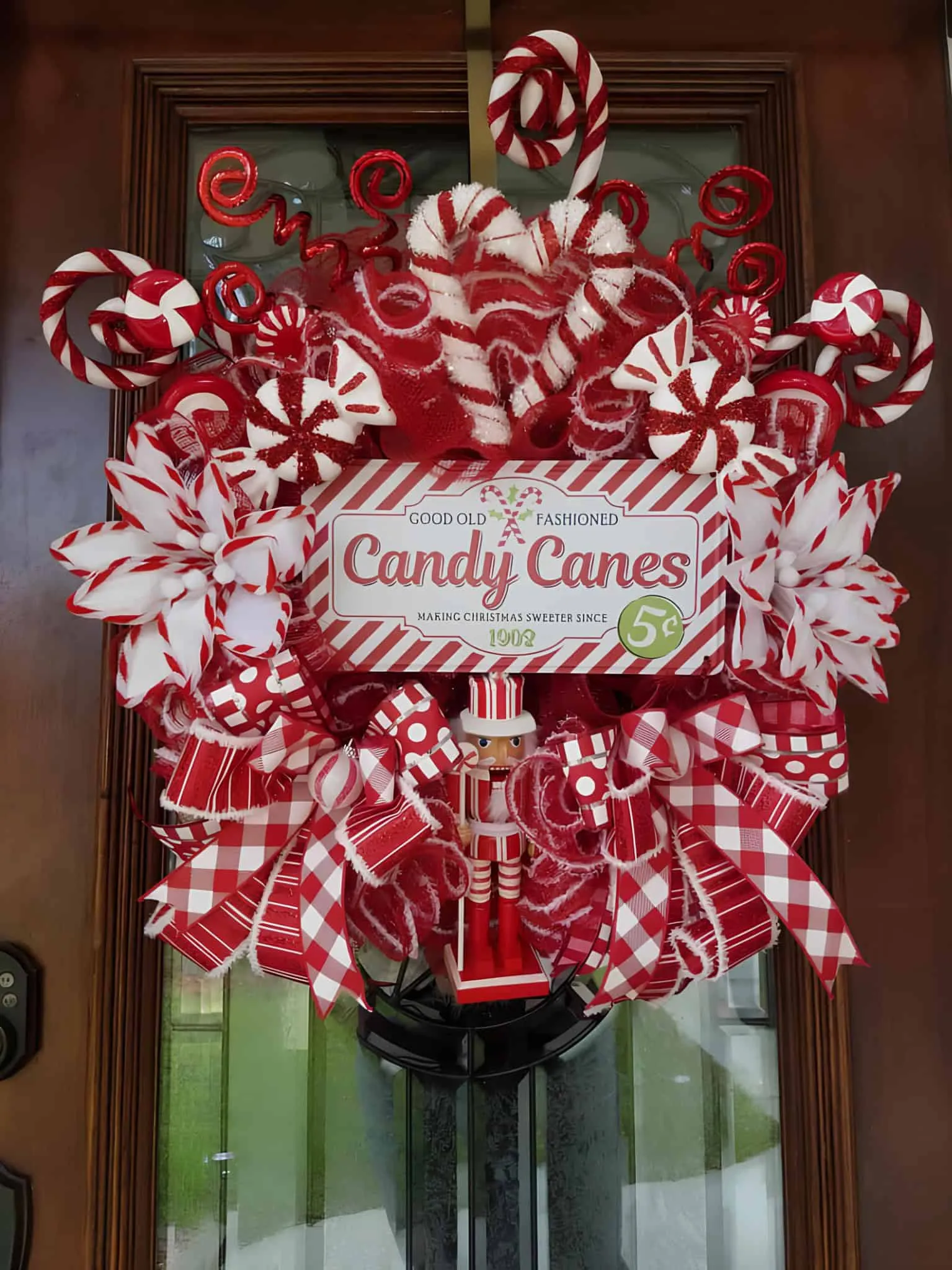 Weihnachtskrone mit Zuckerrutenband Rote und weiße Weihnachtskrone im Zuckerruten-Stil mit Bändern, Pfefferminzmustern und einer Nussknackerfigur