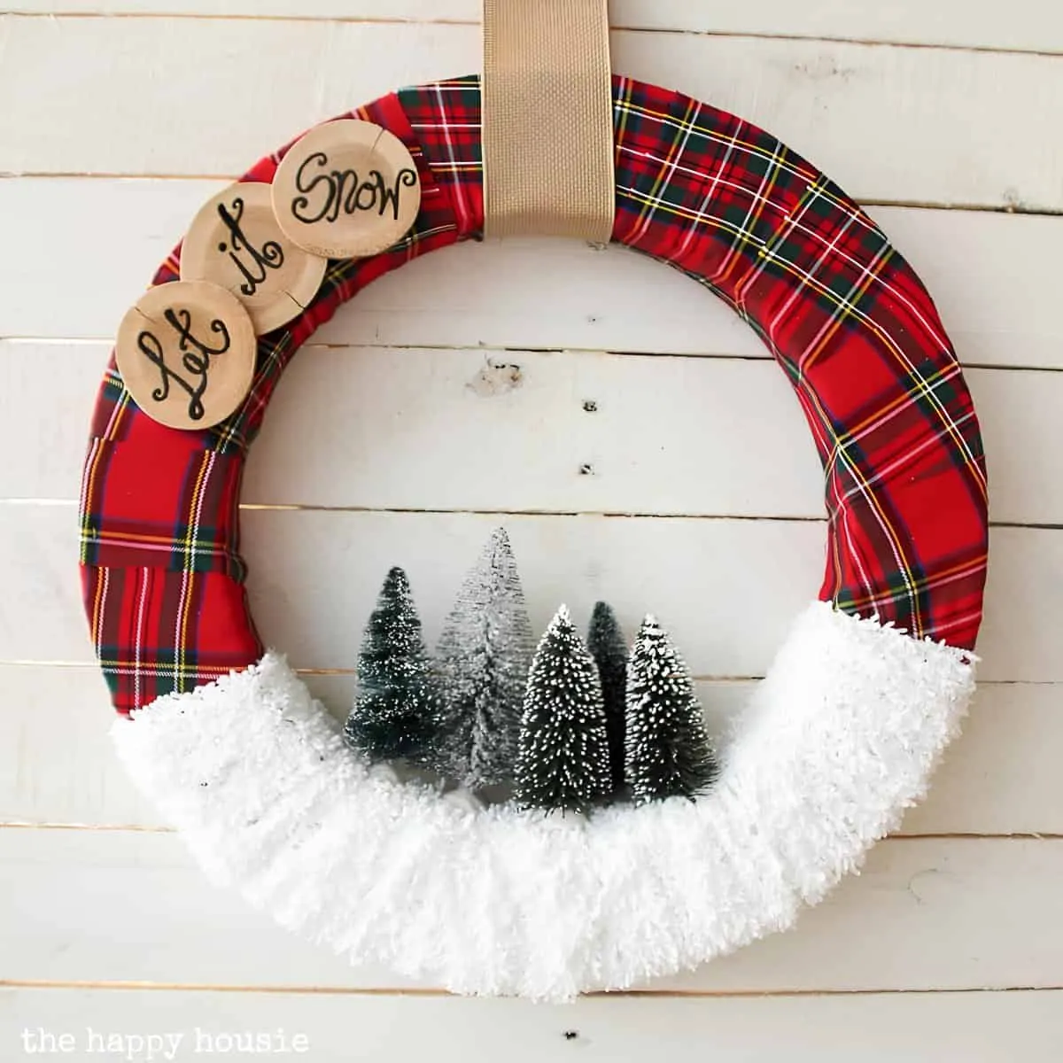 Let It Snow Plaid Christmas Wreath Weihnachtskranz in Karomuster, umhüllt von künstlichem Schnee sowie Bäumen im Stil einer Flaschenbürste