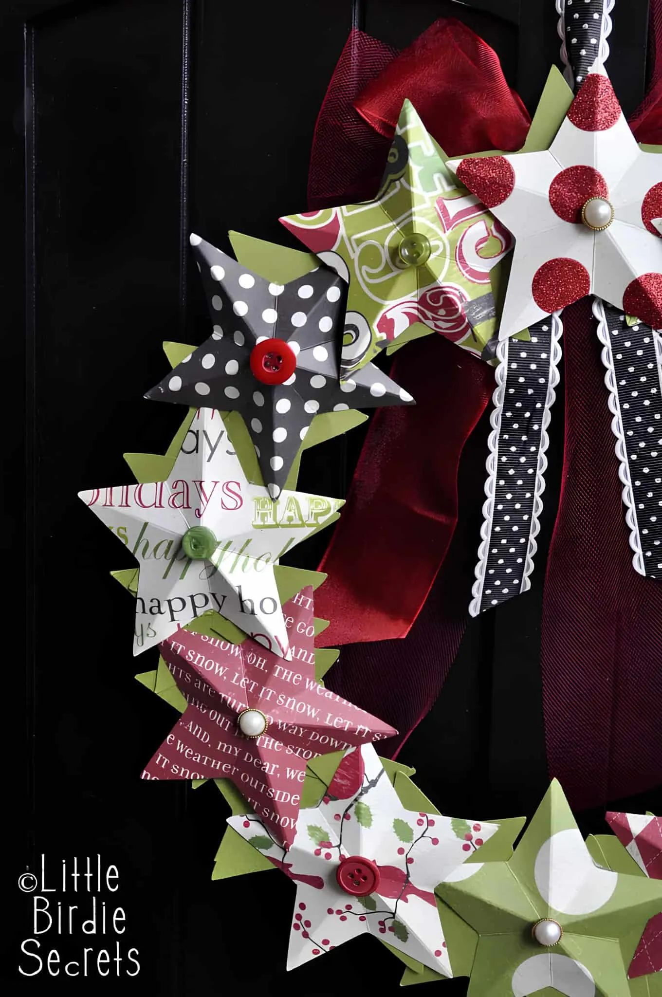 Papier-Stern-Bänder-Winterkränzchen Papier-Stern-Winterkränzchen mit Knöpfen und gepunkteten Bändern in Schwarz, Rot und Grün