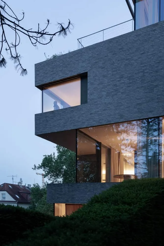 Panorama des Abendkorridors der Villa Vista von Znameni Ctyr Architekti Villa Vista von Znameni Ctyr Architekti, vorkragender Eckbau mit abendlichem Innenlicht in Prag