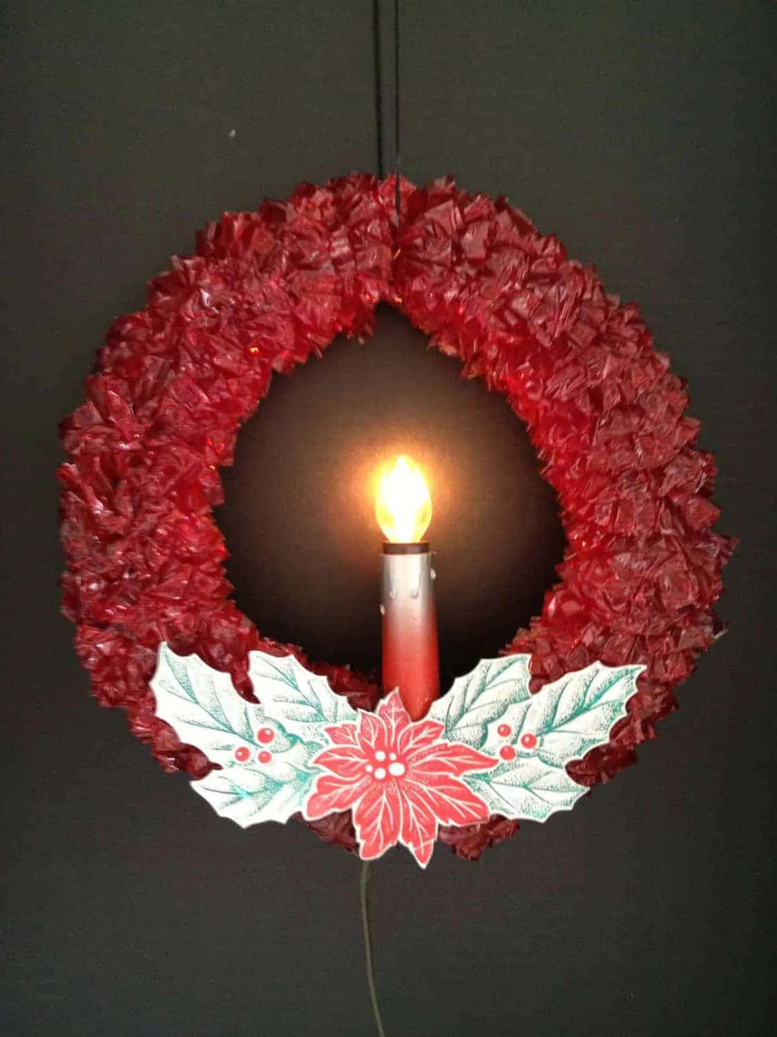 Rote Papier-Weihnachtskrone mit Licht Rote Papierkrone mit zentralem Licht und Stechpalmenmuster