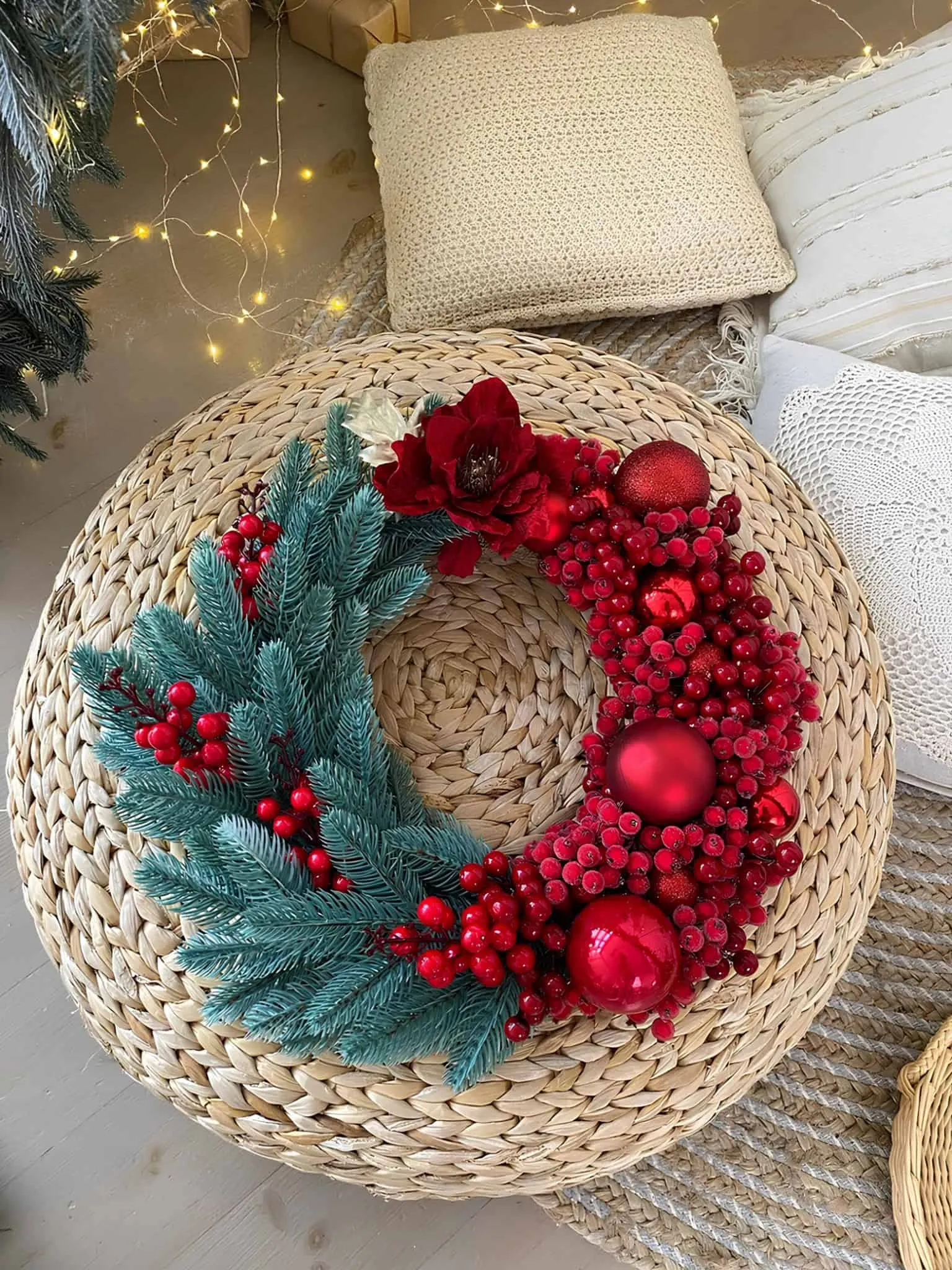 Kranz aus roten Beeren und Kiefernzweigen Halb umwickelter Weihnachtskranz aus roten Beeren mit matten Verzierungen und blaugrünen Kiefernzweigen