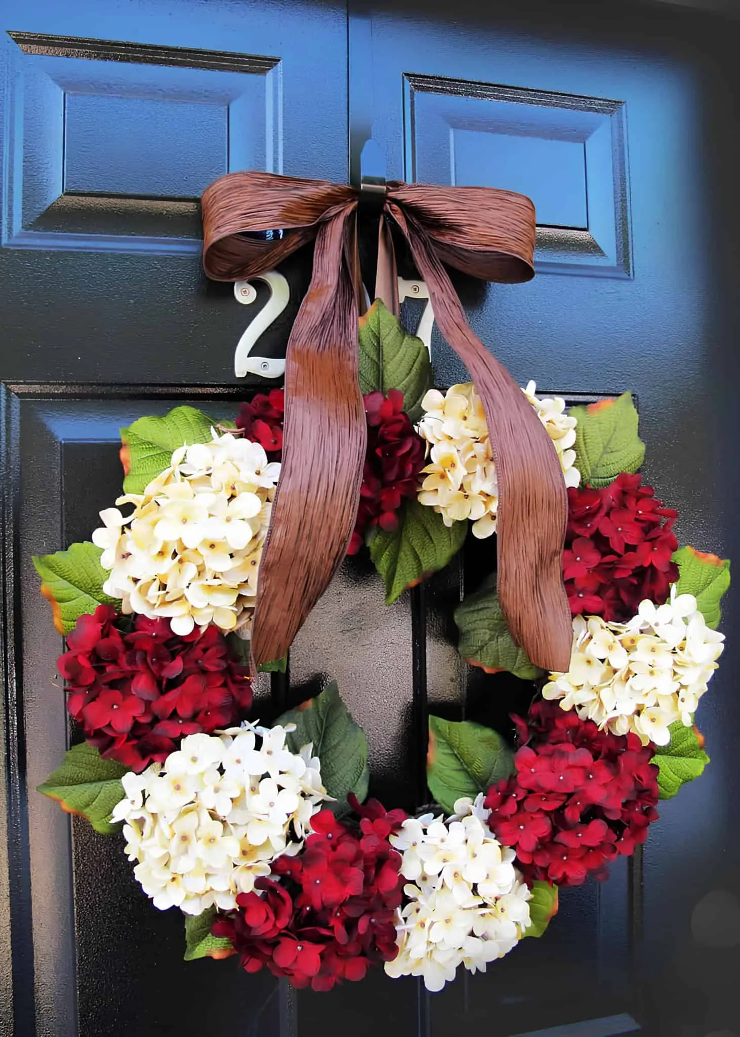 Hydrangeenkranz mit brauner Schleife Klassischer Weihnachtskranz mit cremefarbenen und burgunderfarbenen Hydrangien sowie einem breiten braunen Band