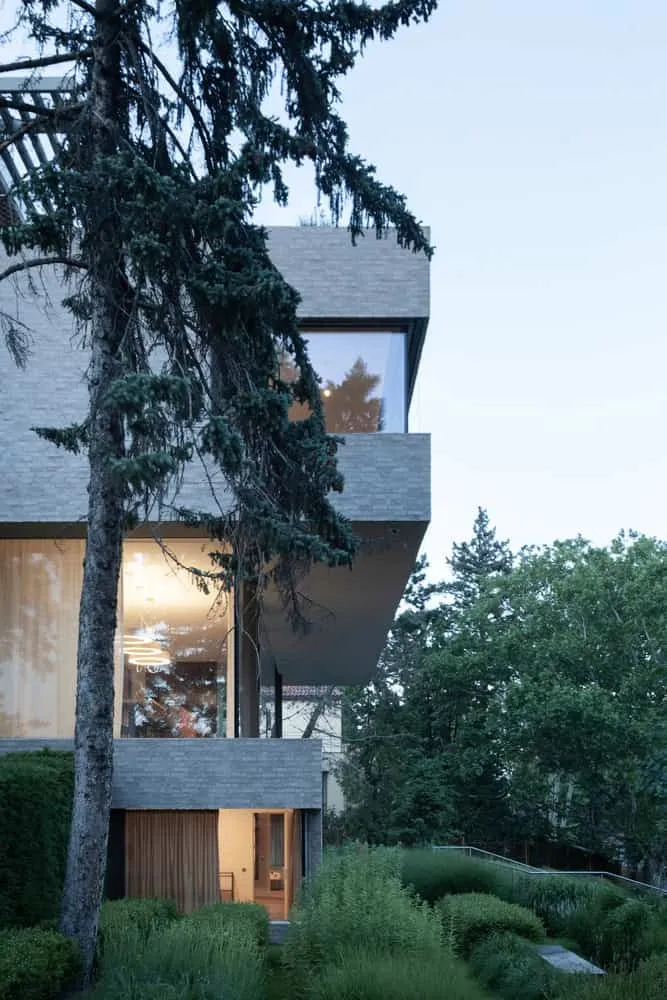 Seitansicht der Villa Vista bei Dämmerung mit Bäumen von Znameni Ctyr Architekti Villa Vista von Znameni Ctyr Architekti, Seitansicht bei Dämmerung umgeben von hohen Bäumen und mehrschichtigen Gebäudeteilen