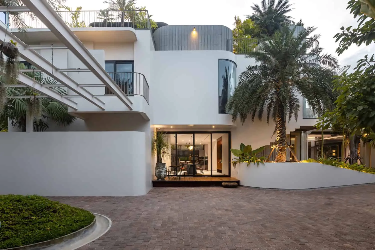 Wat Bo House courtyard facade pergola evening by UAD Architects Wat Bo House by UAD Architects courtyard facade mit Pergola und Palmen am Abend in Kambodschas