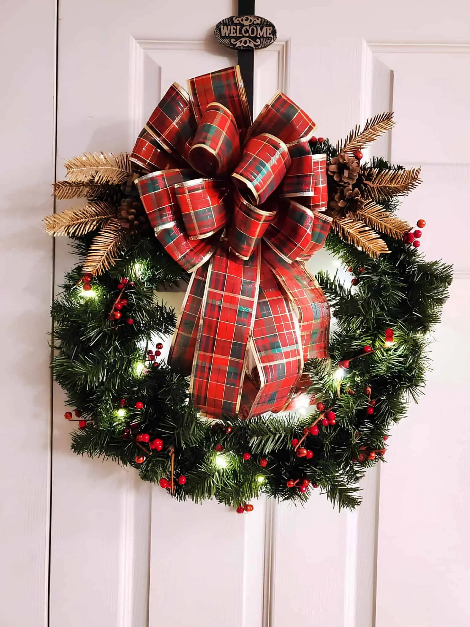 Gekleideter immergrüner Weihnachtskranz mit Tartan-Bow Beleuchteter immergrüner Weihnachtskranz mit rotem Tartan-Bow und Beeren