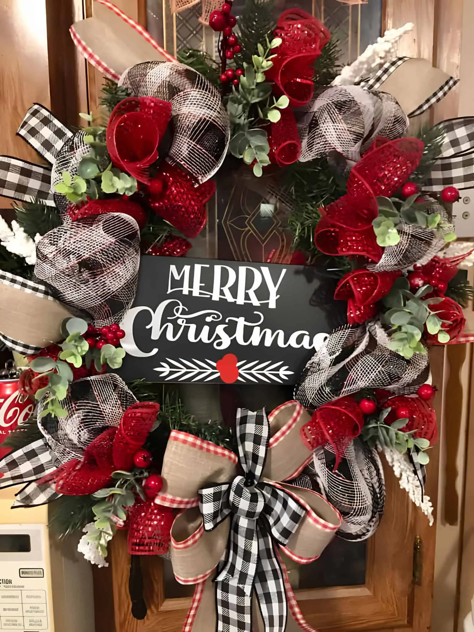 Buffalo-Plaid-Farmhaus-Kranz mit Bändern Lebhafter Weihnachtskranz mit roten und schwarzen karierten, Leinwand- sowie Netzbändern, verziert mit Weihnachtsgrün, Beeren und einem „Frohe Weihnachten“-Schild – perfekt für festliche Heimdekoration.