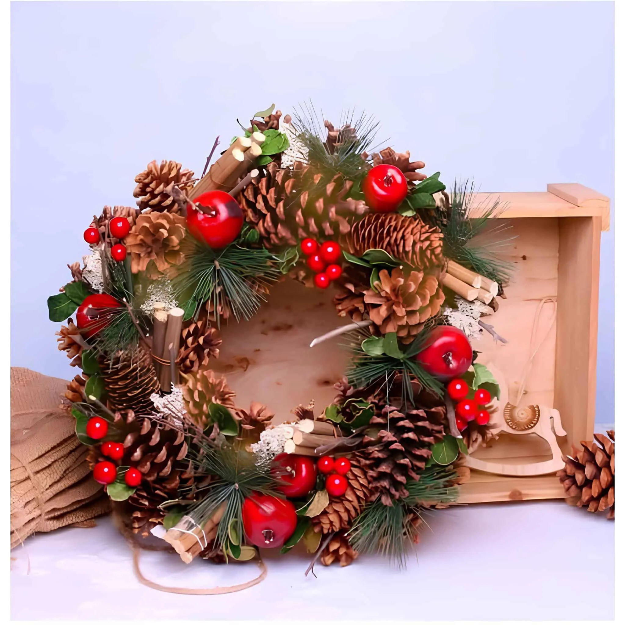 Weihnachtskranz mit Äpfeln, Zimtstangen und Kiefernzapfen Ländlicher Kiefernzapfenkranz mit roten Äpfeln, Zimtstangen und Kiefernzweigen