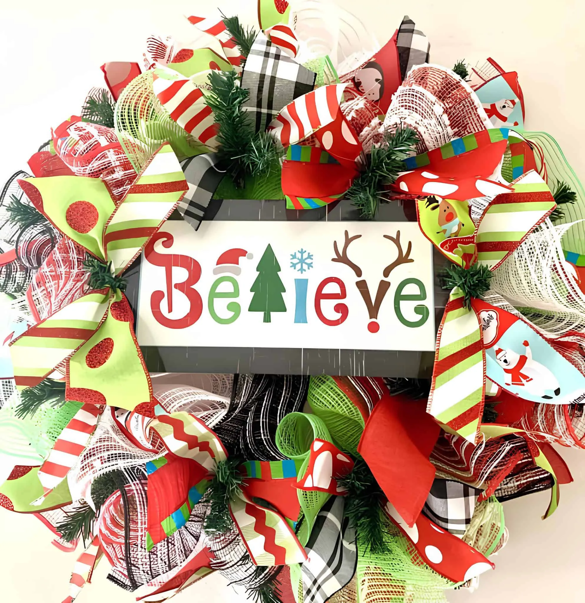 “Believe” Multicolor Ribbon Wreath Leuchtende Bänderkrone mit dem Schriftzug Believe, Karamellstreifen und grünen Akzenten