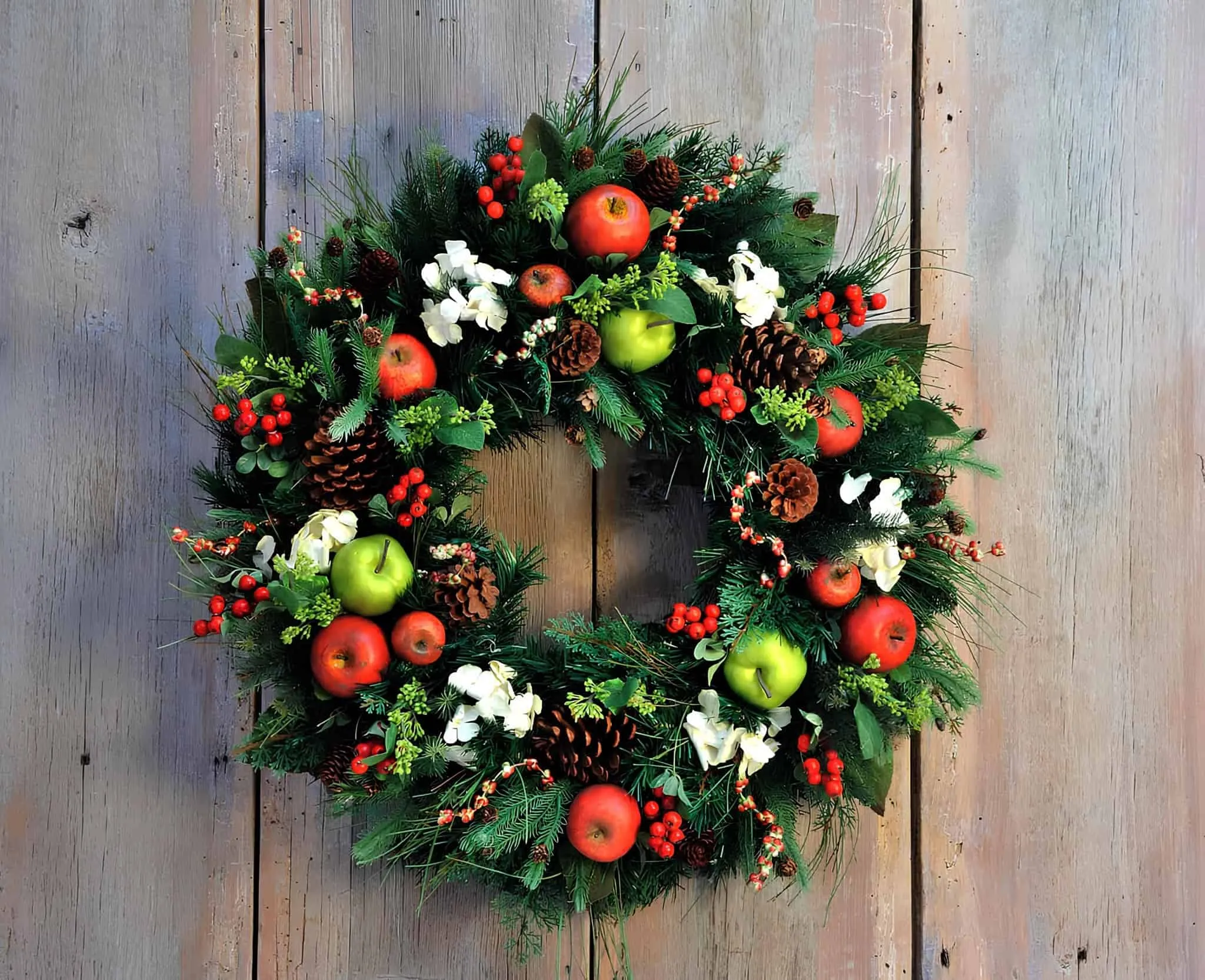 Weihnachtskranz mit Äpfeln, Kiefernzapfen und Beeren Weihnachtskranz mit Äpfeln, Kiefernzapfen, Beeren und winterlichem Grünzeug