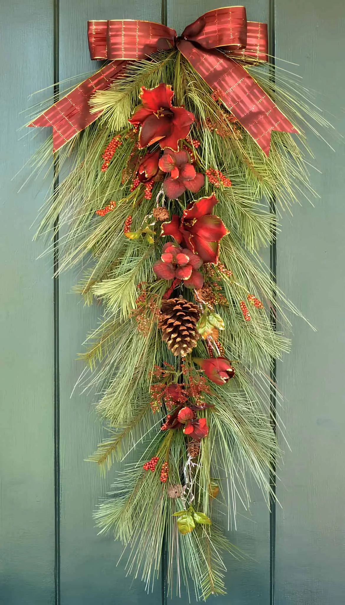 Weihnachtskranz mit roter Schleife und Amaryllis Vertikaler Kranz mit Kiefernholz, roter Amaryllis, Beeren und einer roten Schleife