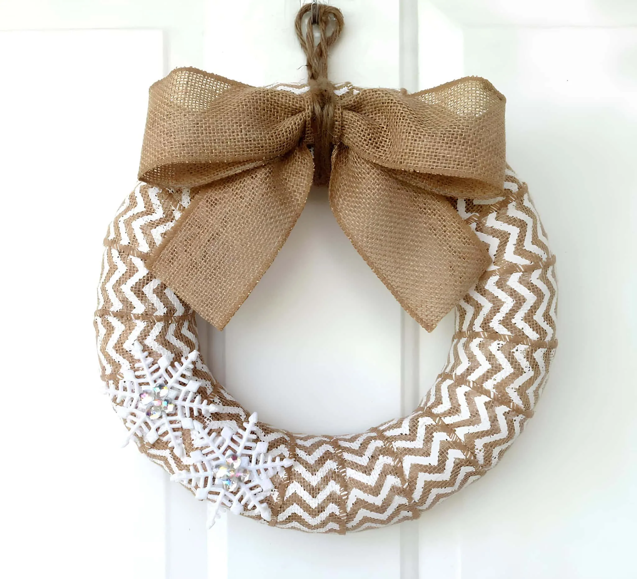 Weißer Chevron-Jutekranz mit Schneeflocken Weißer Chevron-Jutekranz mit Schneeflocken und Jutenschleife
