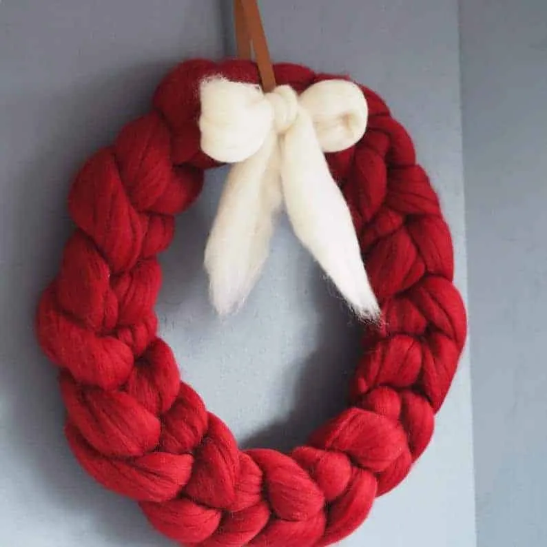 Roter, dicker gestrickter Weihnachtskranz mit weißer Schleife Dicker, roter gestrickter Weihnachtskranz mit weißer Schleife