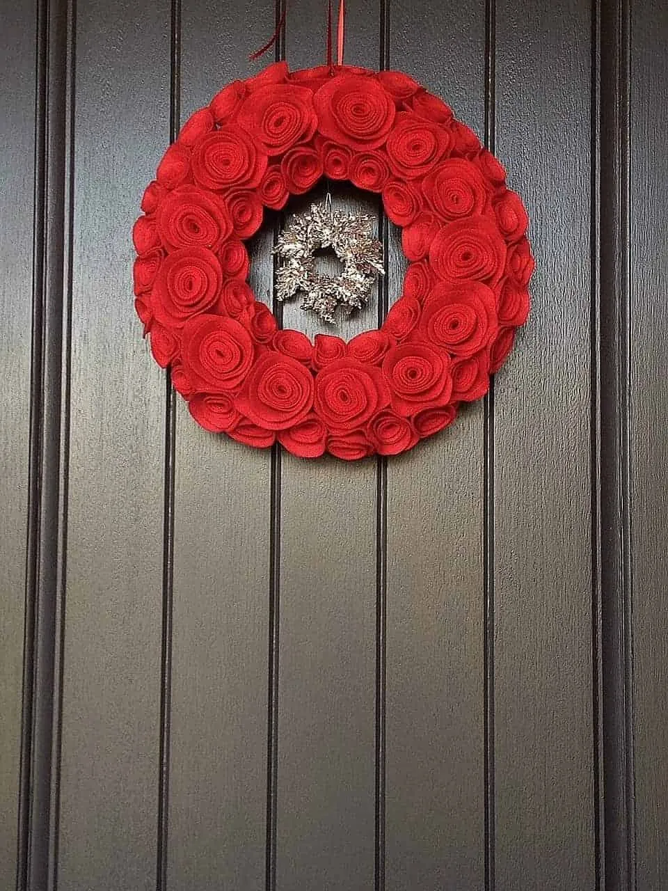 Rote Filzrose-Weihnachtskranz Roter Filzrose-Weihnachtskranz an einer dunklen Holztür