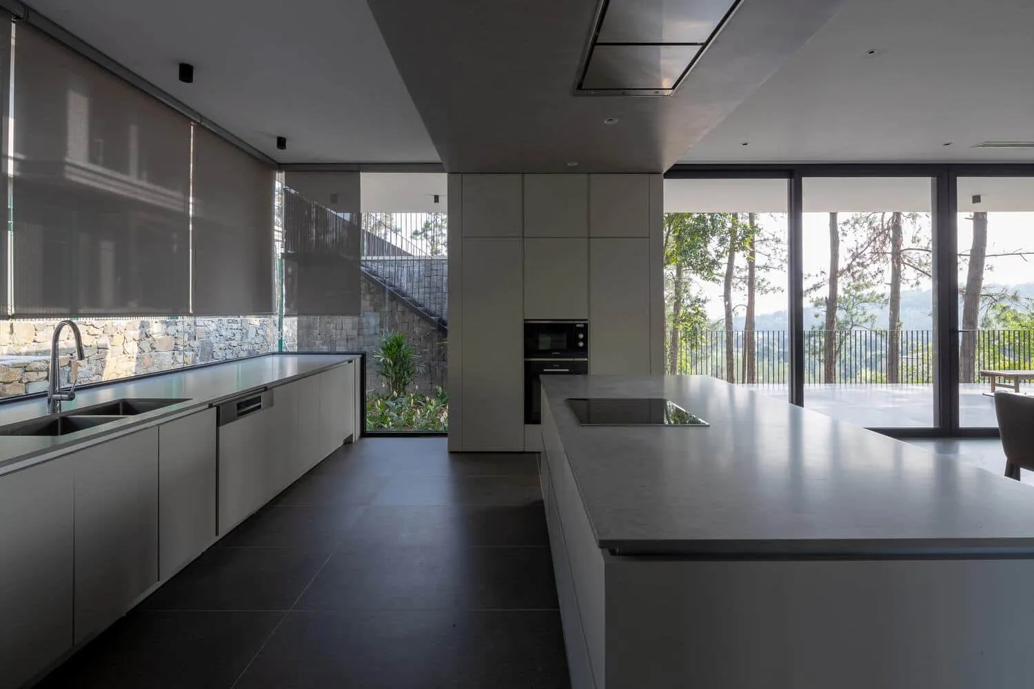 Tam Dao Retreat House minimalistische Küche mit Blick auf den Wald von Idee architects Tam Dao Retreat House von Idee architects: minimalistische Küche mit langer Theke und Blick auf den Wald in Tam Dao, Vietnam