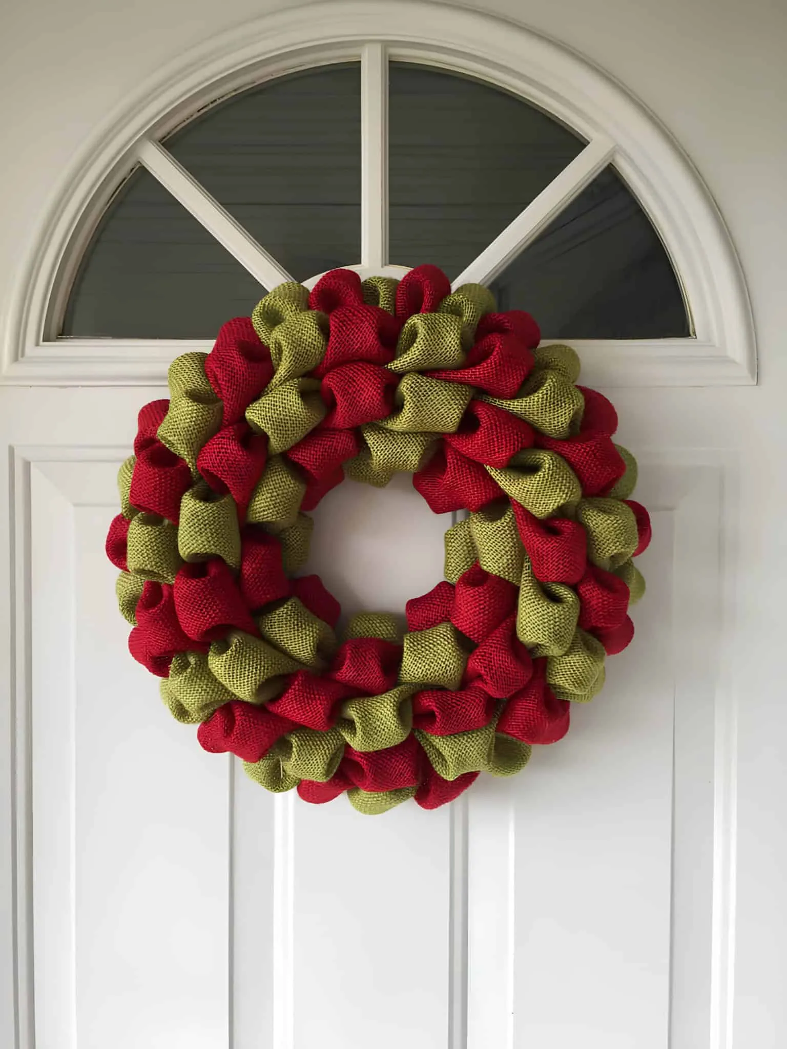 Weihnachtskranz aus Rot- und Grünburlap Ländlicher Weihnachtskranz aus roten und grünen Burlap-Bändern
