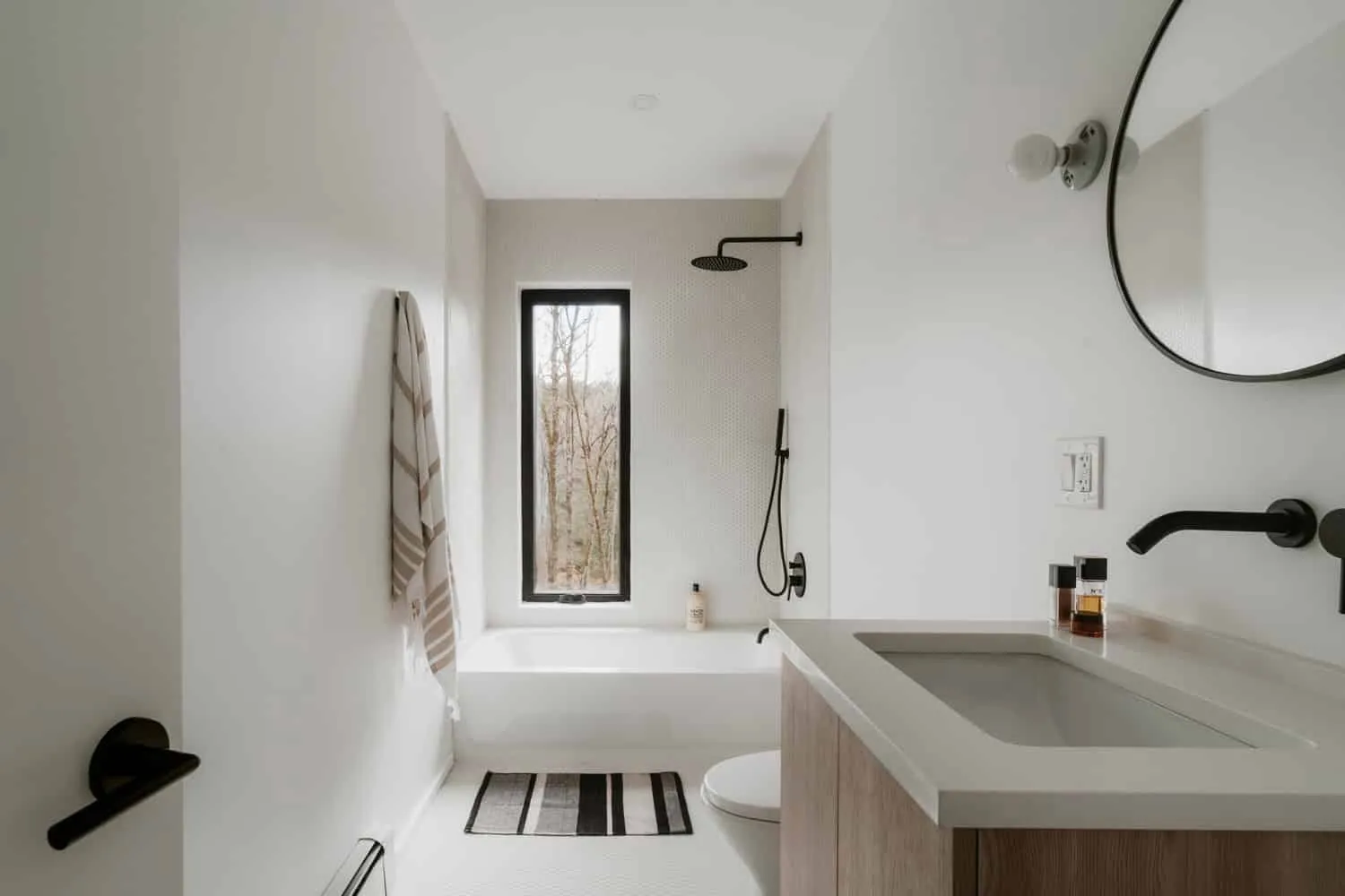 Badezimmer im Forest Edge House mit Badewanne, Entwurf von Marc Thorpe Helles Badezimmer im Forest Edge House mit Badewanne und hohem Fenster zum Wald in New York
