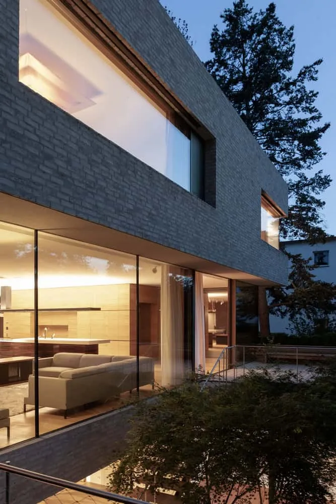 Küche und Wohnbereich der Villa Vista bei Dämmerung von Znameni Ctyr Architekti Villa Vista von Znameni Ctyr Architekti, Blick bei Dämmerung in die offene Küche und den Wohnbereich durch vollhohe Verglasungen