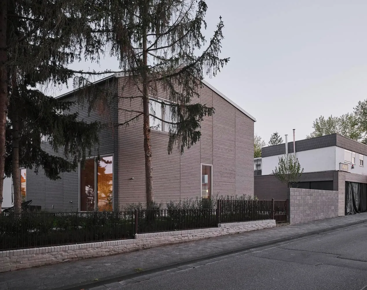 Ein zeitgenössisches modernes Haus mit Naturholzverkleidung, großen Fenstern, minimalistischem Design sowie einem umliegenden Garten, das innovative Wohnarchitektur und nachhaltige Baumaterialien veranschaulicht.